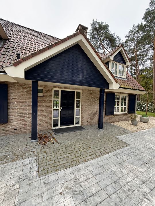 Bakstenen woning met witte ramen en donkere gevelbekleding